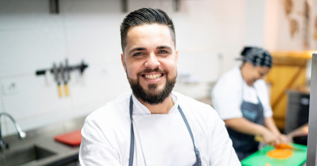 Man smiling toward the camera in facility kitchen.