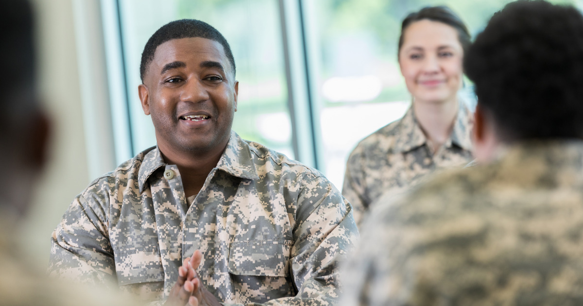 Military members sitting in an office talking.