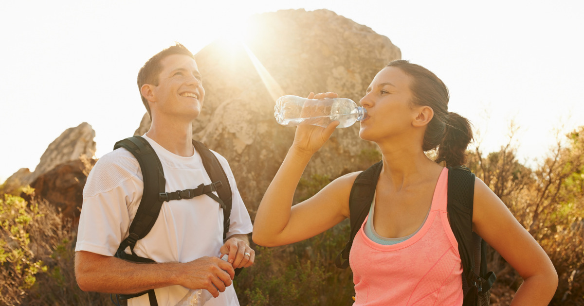 Couple hydrating with water during a hike.