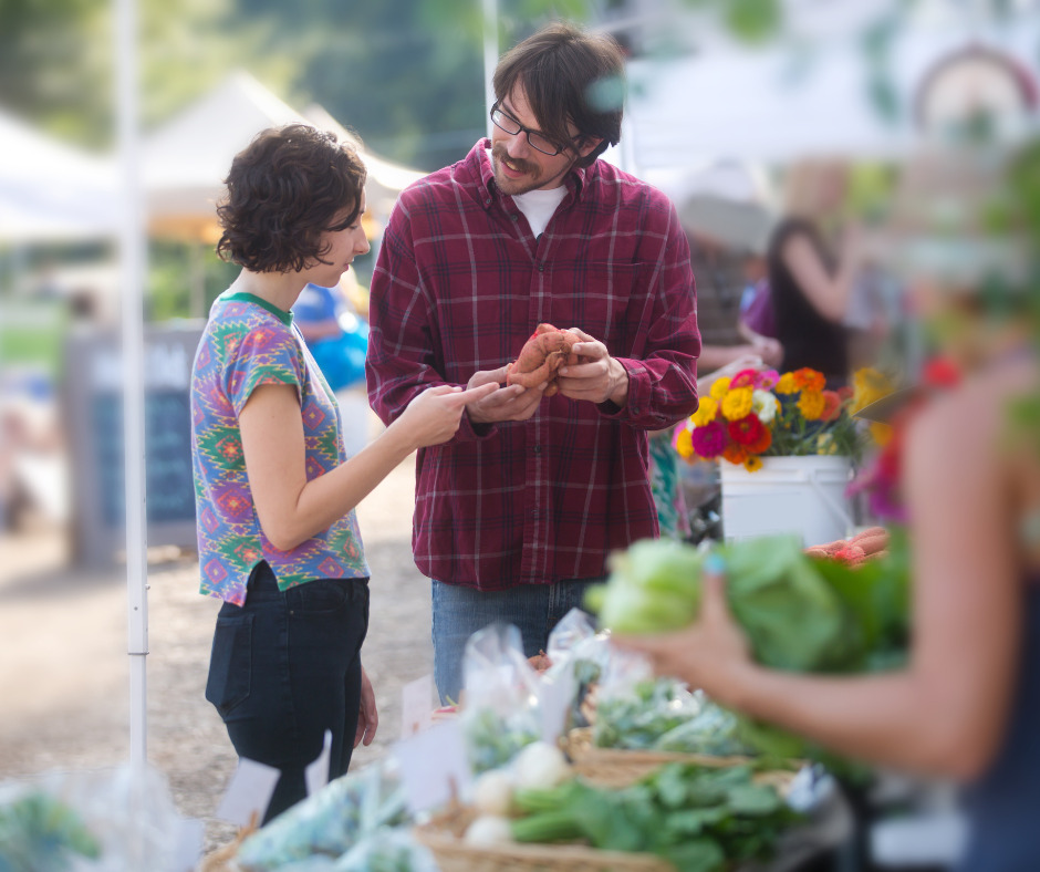 A farmers market vendor speaking with a customer. Vendors can also share useful insights, like creative recipes or storage tips.