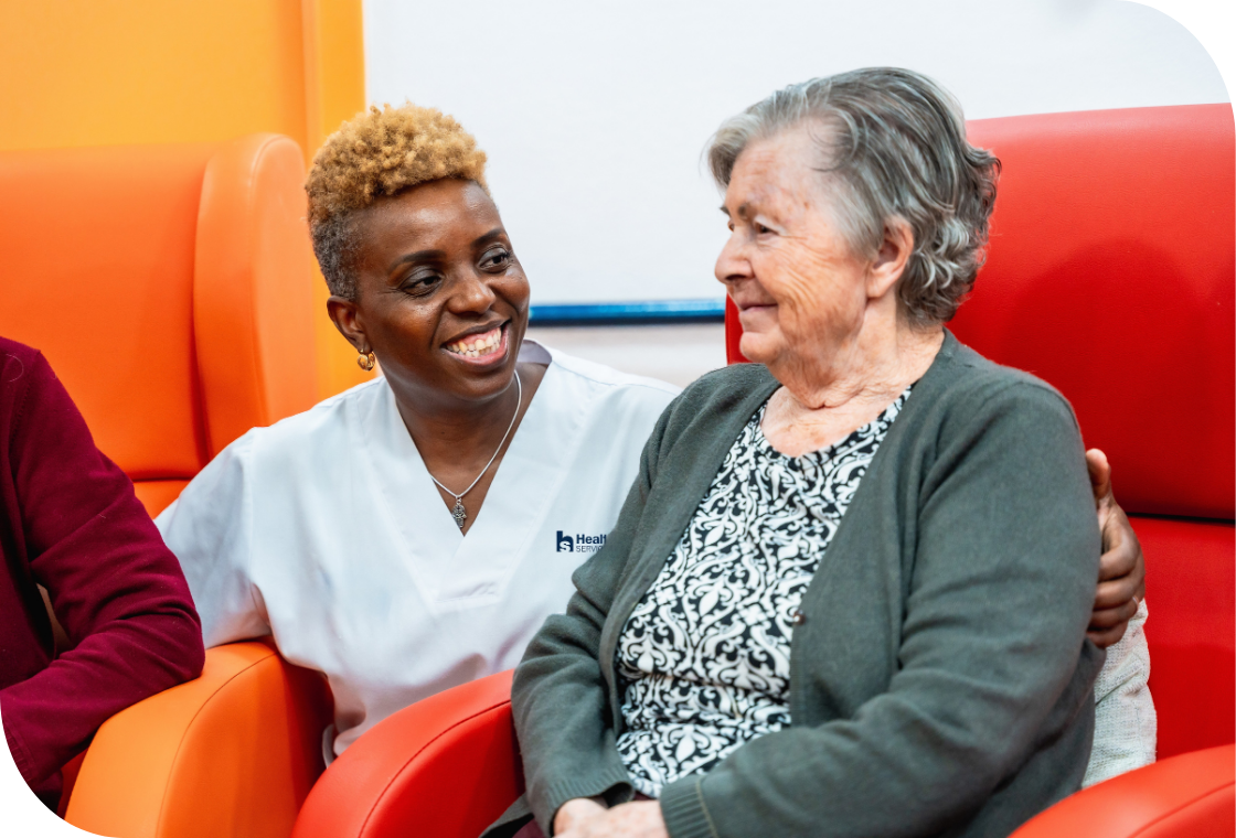 Smiling caregiver warmly interacts with a senior woman in a healthcare setting. Compassionate care and positive engagement in a senior living community.