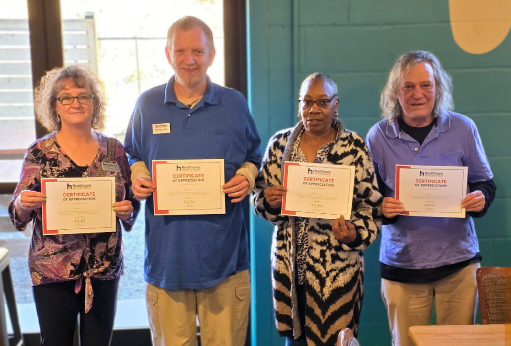 Four smiling HCSG staff members proudly display their Certificates of Appreciation. Recognizing the dedicated and valued employees of Healthcare Services Group for their contributions.