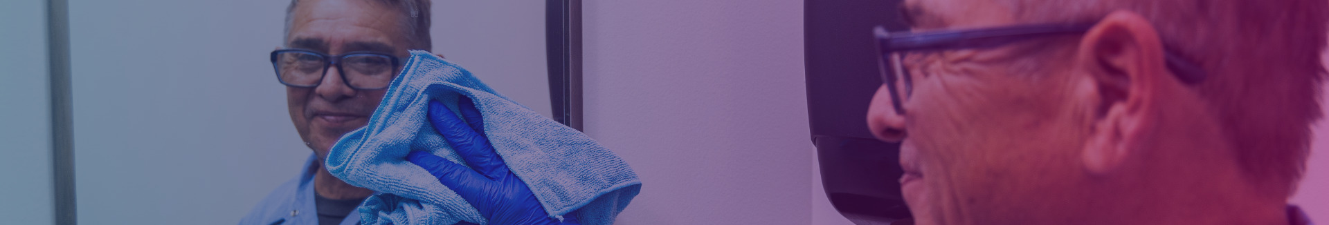 A close-up shows a hand wearing a blue glove cleaning a mirror with a blue cloth. Meticulous cleaning and maintenance services provided by HCSG.